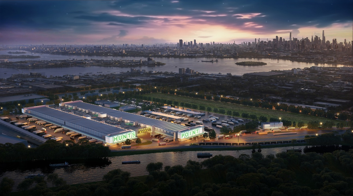 Aerial view at dusk of a large industrial complex labeled HUNTS POINT, with trucks and warehouses, set near a river and city skyline in the background. The sky is colorful with city lights starting to appear.