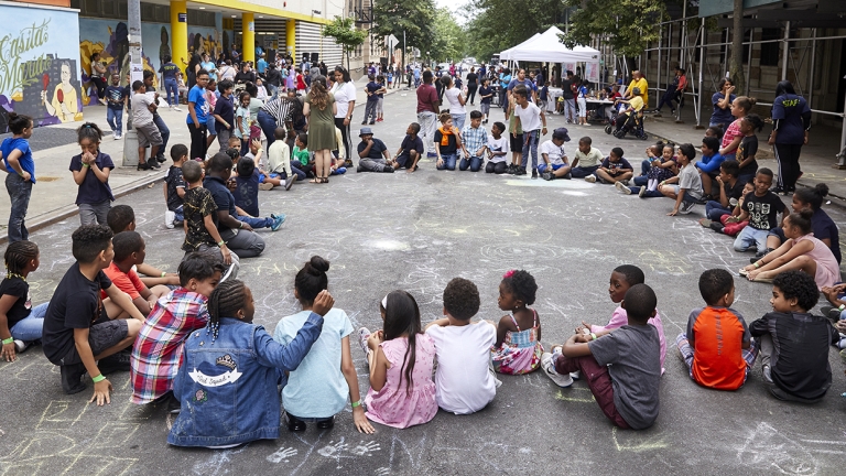 Children sitting in a circle playing with chalk.