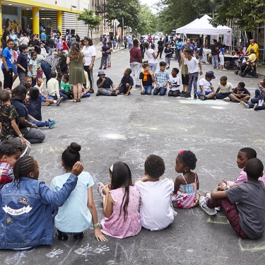 Children sitting in a circle playing with chalk.