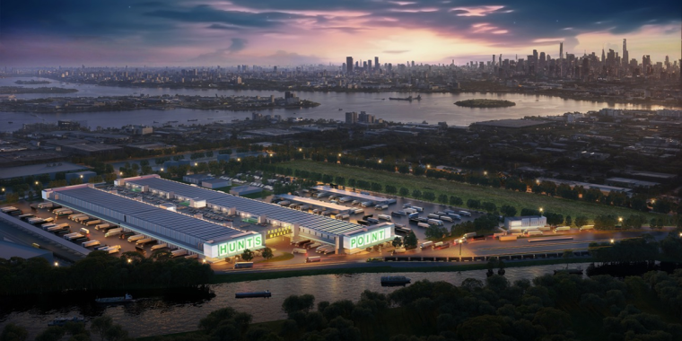 Aerial view at dusk of a large industrial complex labeled HUNTS POINT, with trucks and warehouses, set near a river and city skyline in the background. The sky is colorful with city lights starting to appear.